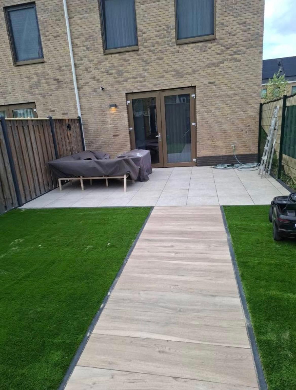 Aangelegde achtertuin met terras, kunstgras en houtlook tegelpad